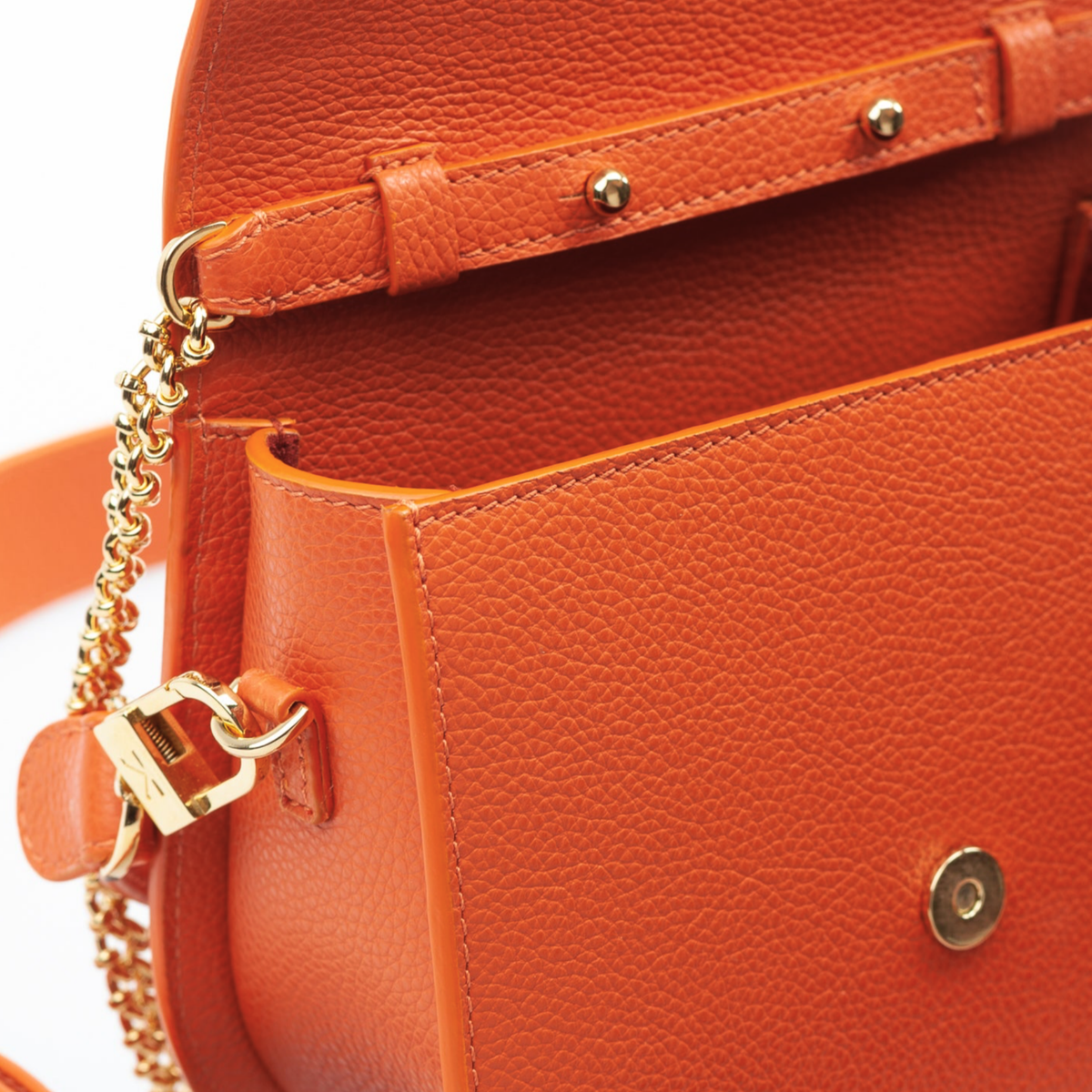Interior of Ella Wave Saddle Bag showing microsuede lining and open pocket. Removable Crossbody chain strap and removable leather shoulder strap. (Toasted Orange Pebble Leather)