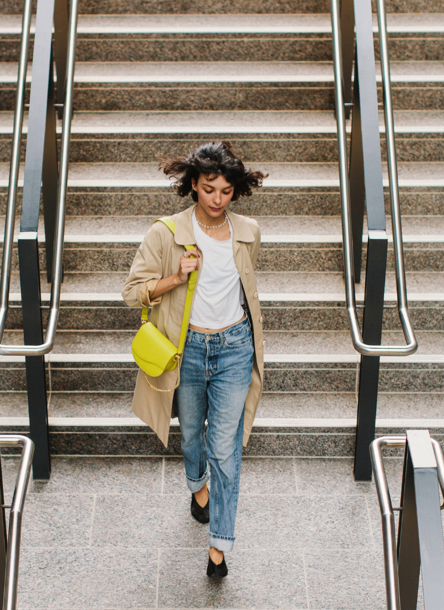 Lifestyle: Ariana Wave Saddle, Pebble Chartreuse leather lifestyle worn as a leather crossbody bag. The Well, Staircase.