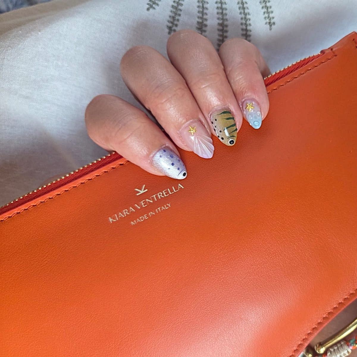 Marea Wave Pouch in Toasted Orange Smooth Leather, hand holding the pouch.