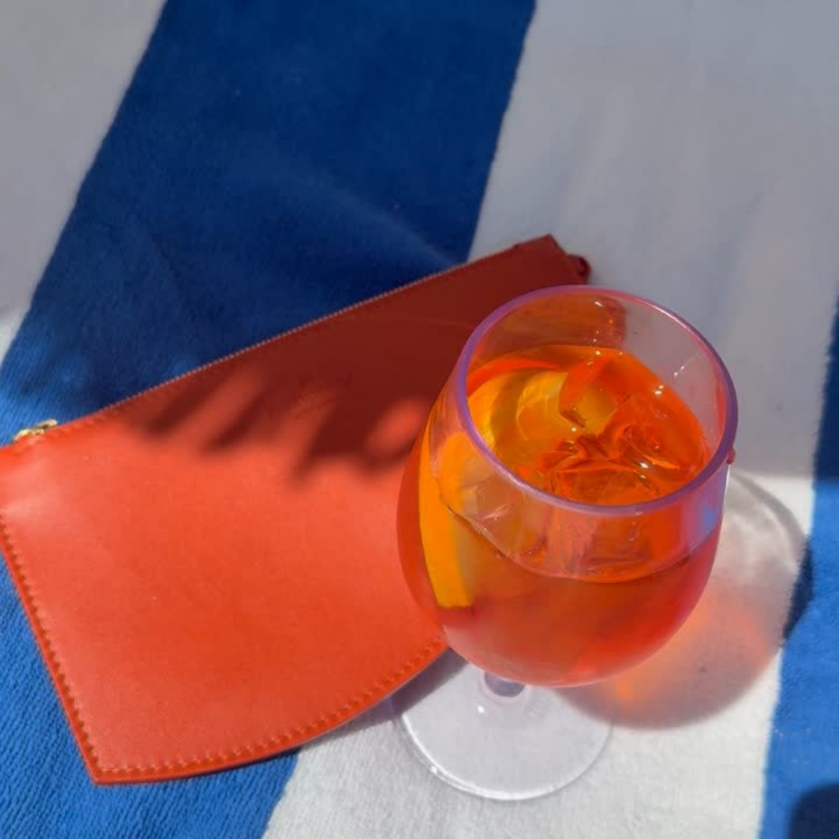 Video of Marea Wave Pouch at the beach next to an Aperol Spritz. Can be used as a hand fan.
